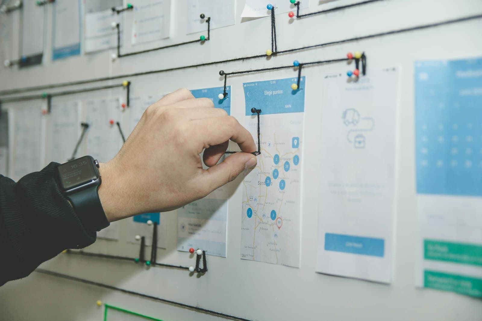 Hand verbindt schermschetsen met touwtjes op een planbord
