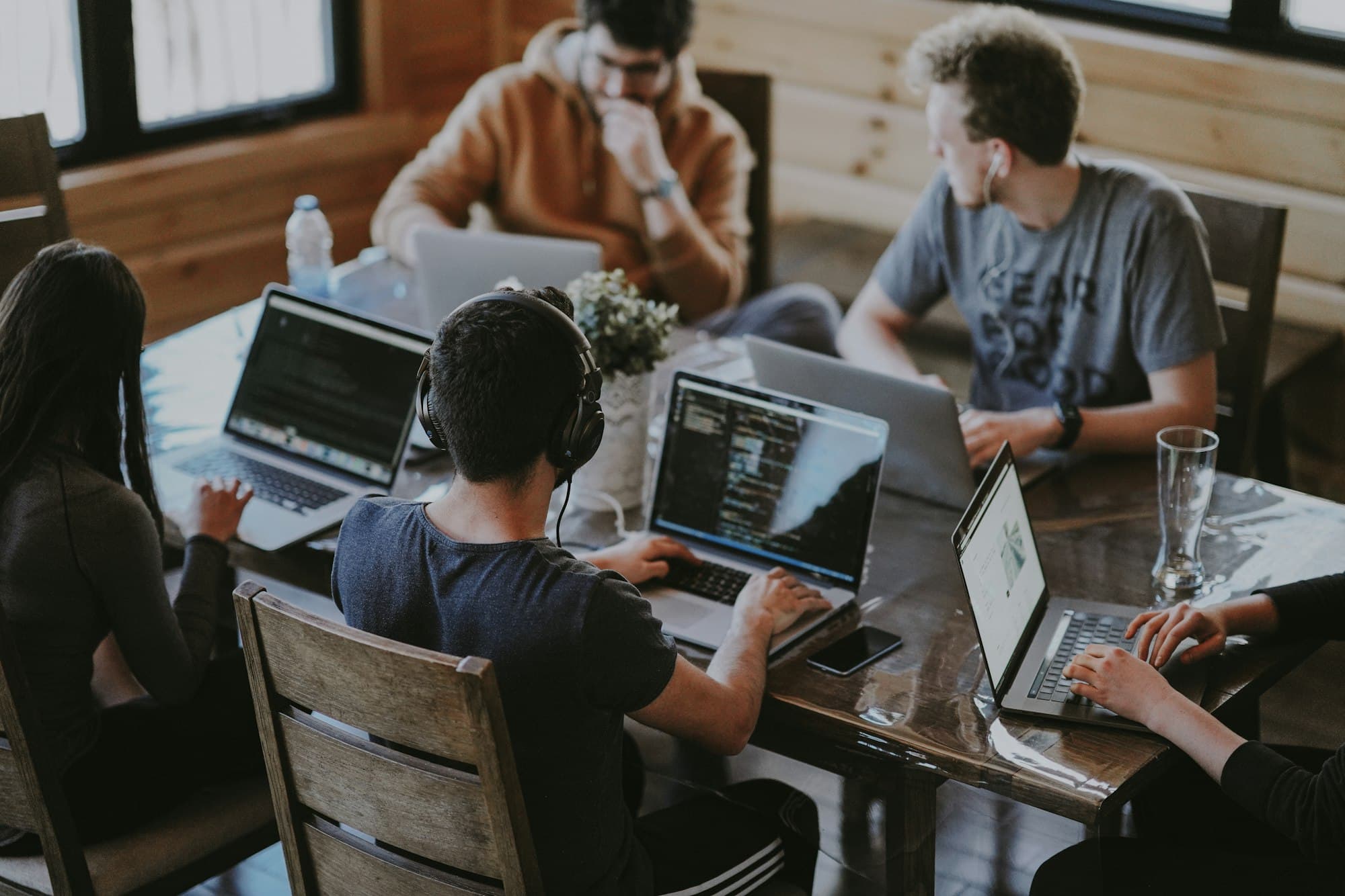 Team werkt samen aan laptops rond een houten tafel