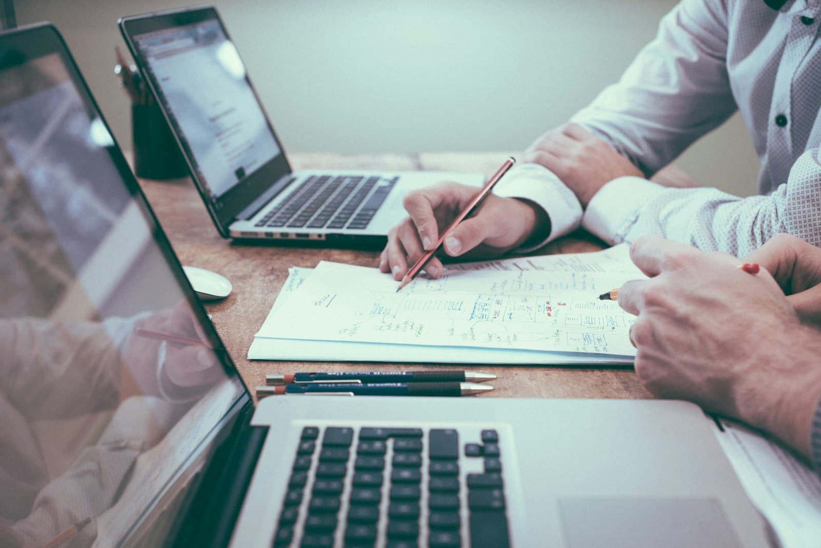 Twee mensen werken een plan uit op papier, naast hun laptops