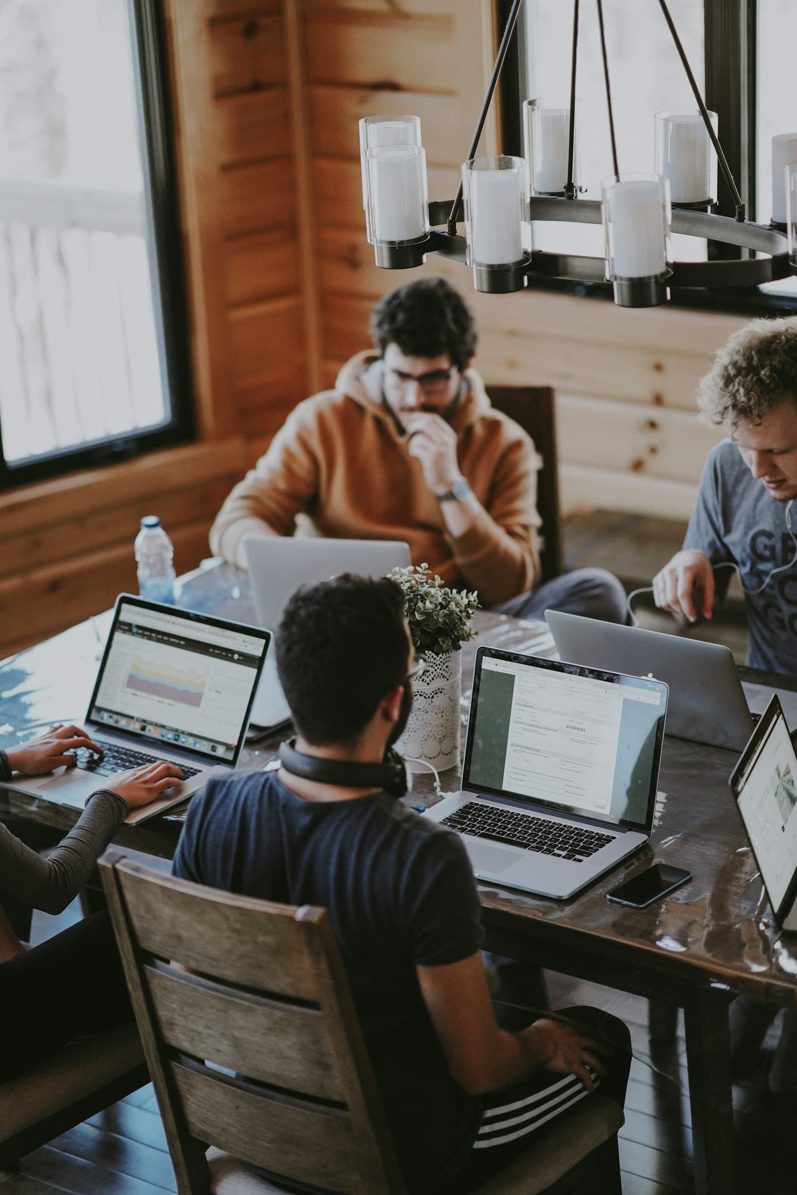 Team werkt geconcentreerd aan laptops rond een houten tafel